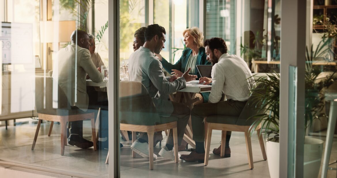 Staff sitting around a table in their office, chatting about how they plan to invest in 2026 and beyond