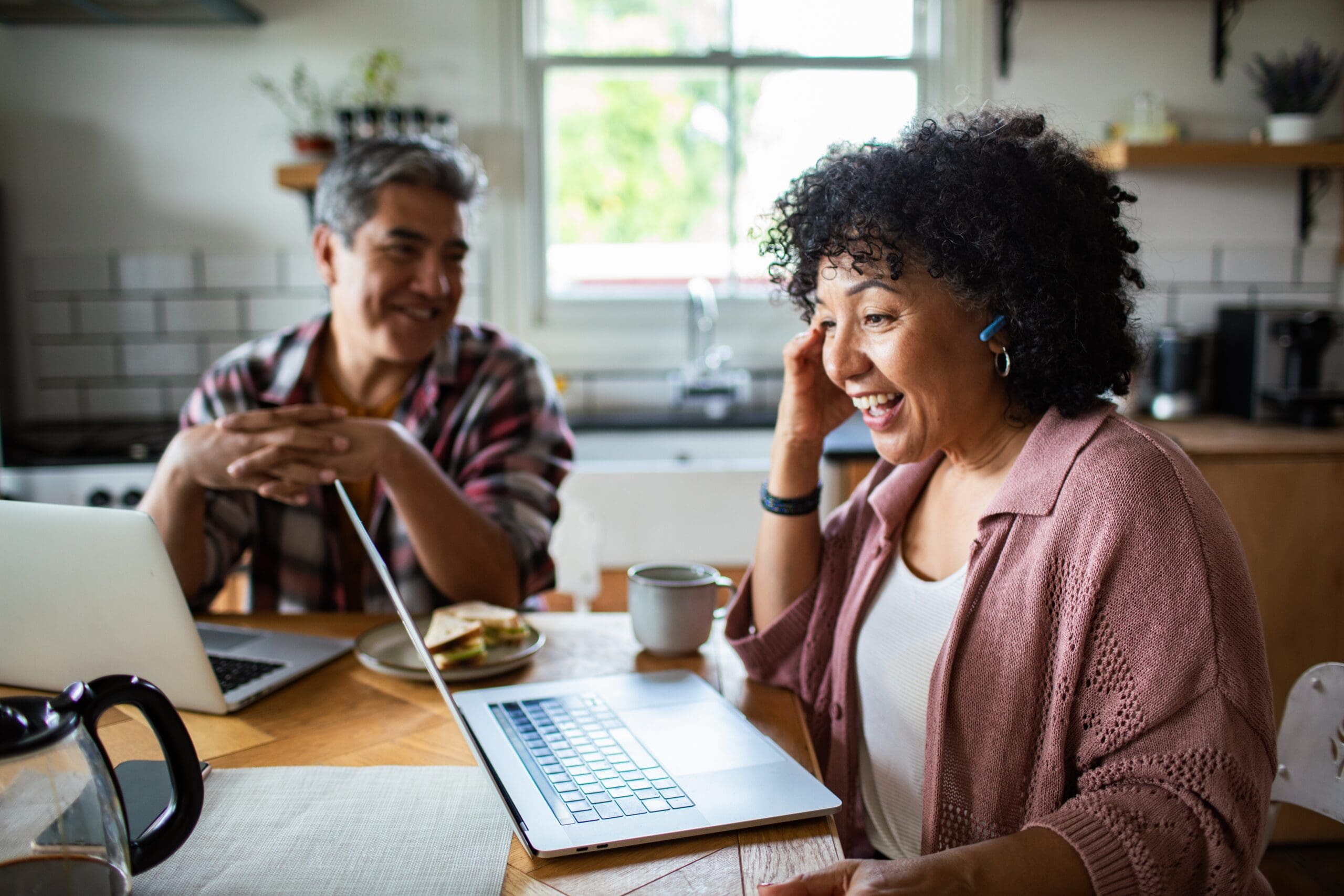 Couple reviewing their finances on laptops at home to boost pension savings before the tax year end deadline